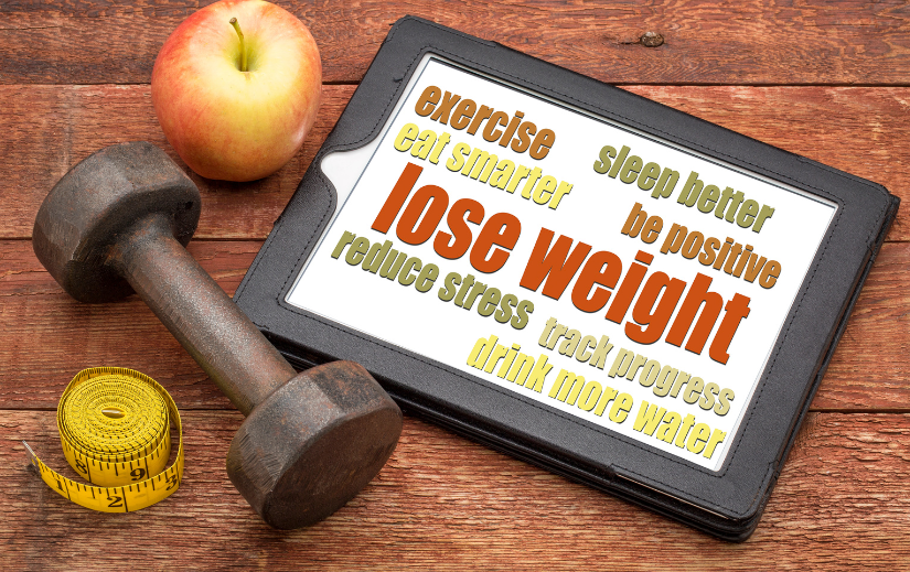 Faceless YouTube channel idea with weight loss tips on a tablet, dumbbell, apple, and measuring tape on a wooden table.